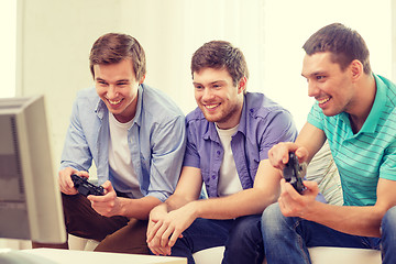 Image showing smiling friends playing video games at home