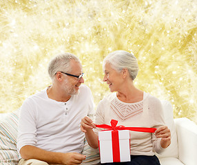 Image showing happy senior couple with gift box at home