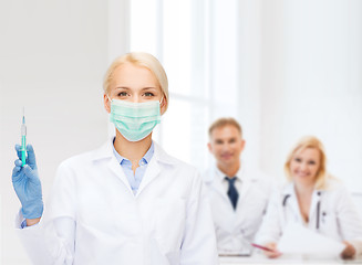 Image showing doctor in mask holding syringe with injection