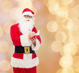 Image showing man in costume of santa claus with notepad
