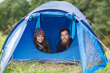 Image showing smiling couple of tourists looking out from tent