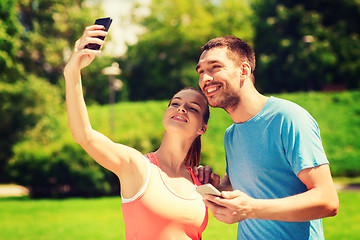 Image showing two smiling people with smartphones outdoors