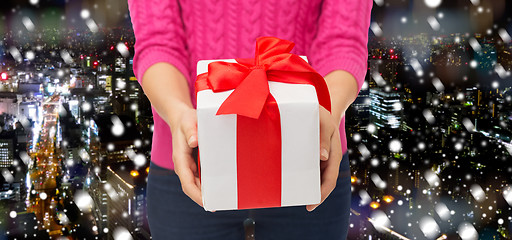 Image showing close up of woman in pink sweater holding gift box