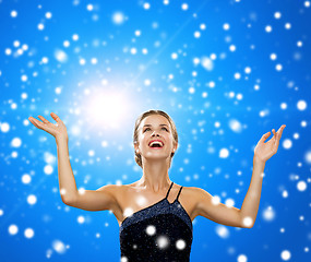 Image showing smiling woman raising hands and looking up