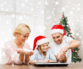 Image showing happy family in santa helper hats cooking