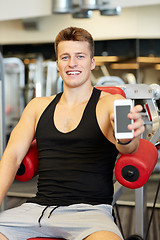 Image showing smiling young man with smartphone in gym