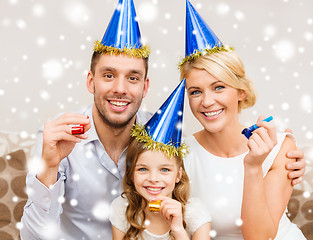 Image showing smiling family in party hats blowing favor horns