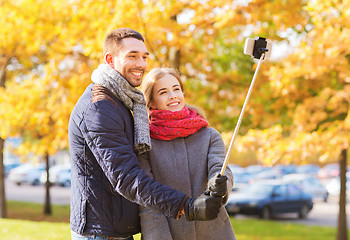 Image showing smiling couple with smartphone in autumn park