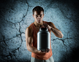 Image showing young male bodybuilder holding jar with protein