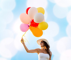 Image showing smiling young woman in sunglasses with balloons