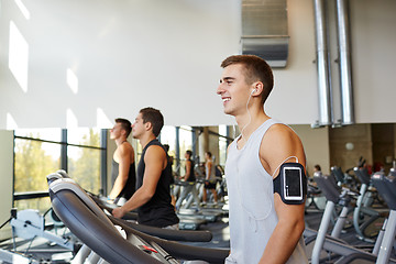 Image showing man with smartphone exercising on treadmill in gym