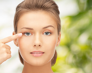 Image showing beautiful young woman pointing finger to her eye