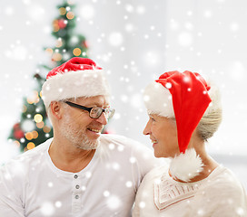 Image showing happy senior couple in santa helper hats at home