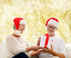 Image showing happy senior couple in santa hats with gift box