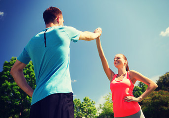 Image showing two smiling people making high five outdoors