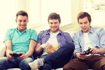 Image showing smiling friends playing video games at home