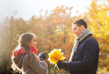 Image showing smiling couple with bunch of leaves in autumn park