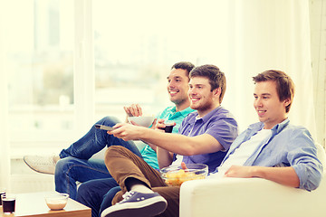 Image showing smiling friends with remote control at home