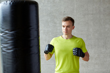 Image showing young man in gloves boxing with punching bag