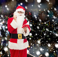 Image showing man in costume of santa claus with notepad