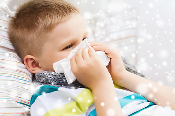 Image showing ill boy blowing nose with tissue at home