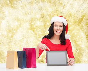 Image showing smiling woman in santa hat with bags and tablet pc