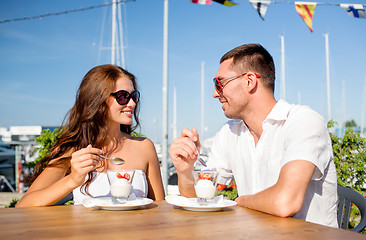 Image showing smiling couple eating dessert at cafe