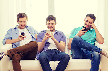 Image showing smiling friends with smartphones at home