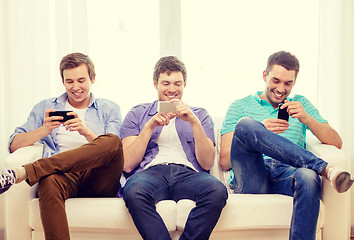 Image showing smiling friends with smartphones at home