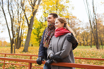 Image showing smiling couple hugging on bridge in autumn park