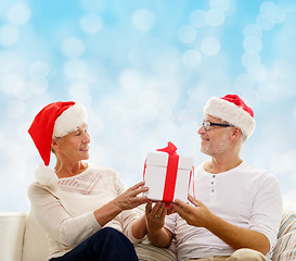 Image showing happy senior couple in santa hats with gift box