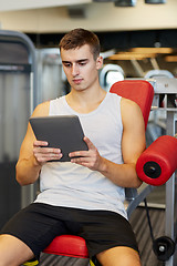 Image showing young man with tablet pc computer in gym