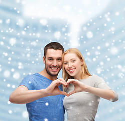 Image showing happy couple making heart gesture and hugging