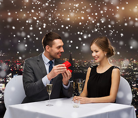Image showing smiling couple with red gift box at restaurant