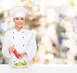 Image showing smiling female chef spicing vegetable salad