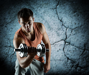 Image showing young man with dumbbell flexing biceps