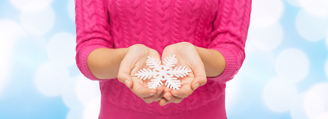 Image showing close up of woman in sweater holding snowflake