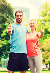 Image showing smiling couple showing thumbs up outdoors