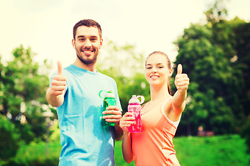 Image showing smiling couple with bottles of water outdoors