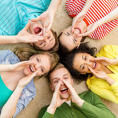 Image showing smiling people lying down on floor and screaming