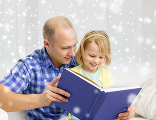 Image showing smiling father and daughter with book at home