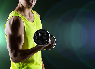 Image showing close up of young man with dumbbell flexing biceps