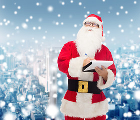 Image showing man in costume of santa claus with notepad