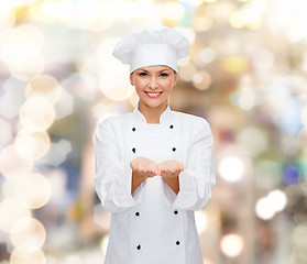 Image showing smiling female chef holding something on hands