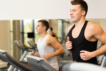 Image showing smiling men exercising on treadmill in gym