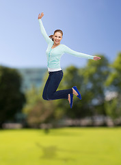 Image showing smiling young woman jumping in air