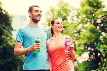 Image showing smiling couple with bottles of water outdoors