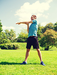 Image showing smiling man stretching outdoors