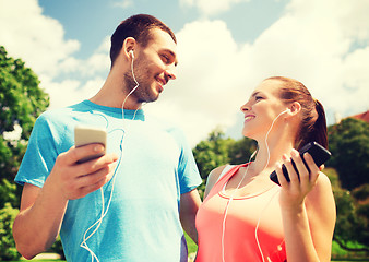 Image showing two smiling people with smartphones outdoors