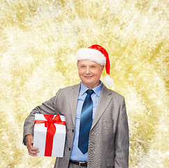 Image showing smiling man in suit and santa helper hat with gift